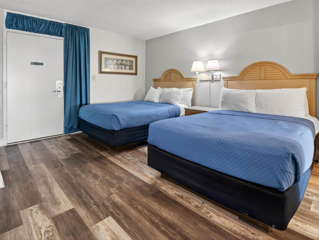 Furnished bedroom with two beds and wood-look flooring