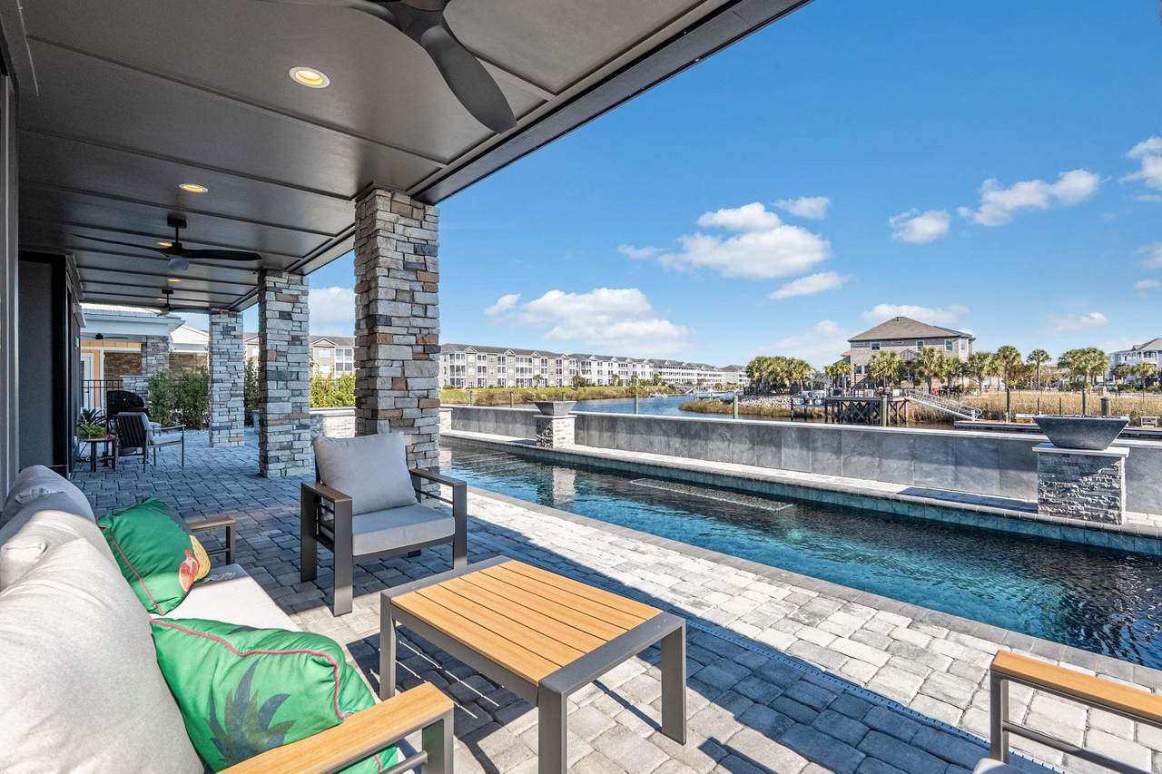 Twilight view of the pool, decks and waterfront side of the home