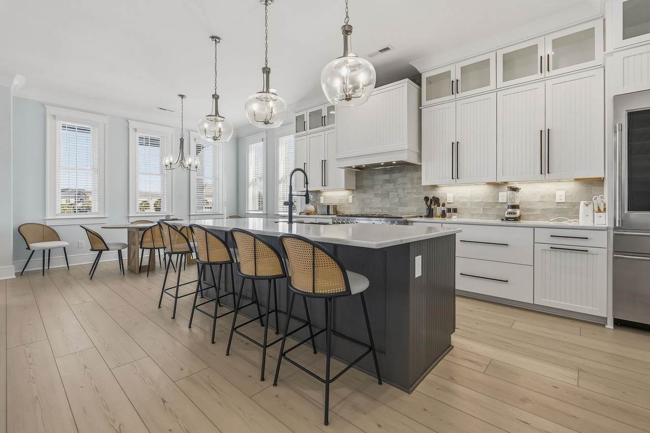 Gas range with a wide metal hood and white cabinetry
