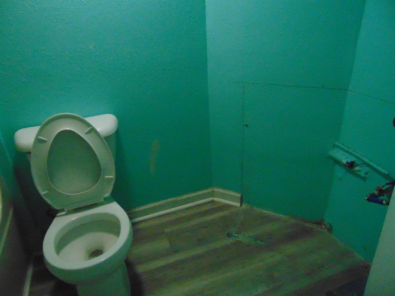 Bathroom area with toilet and unfinished wall surfaces