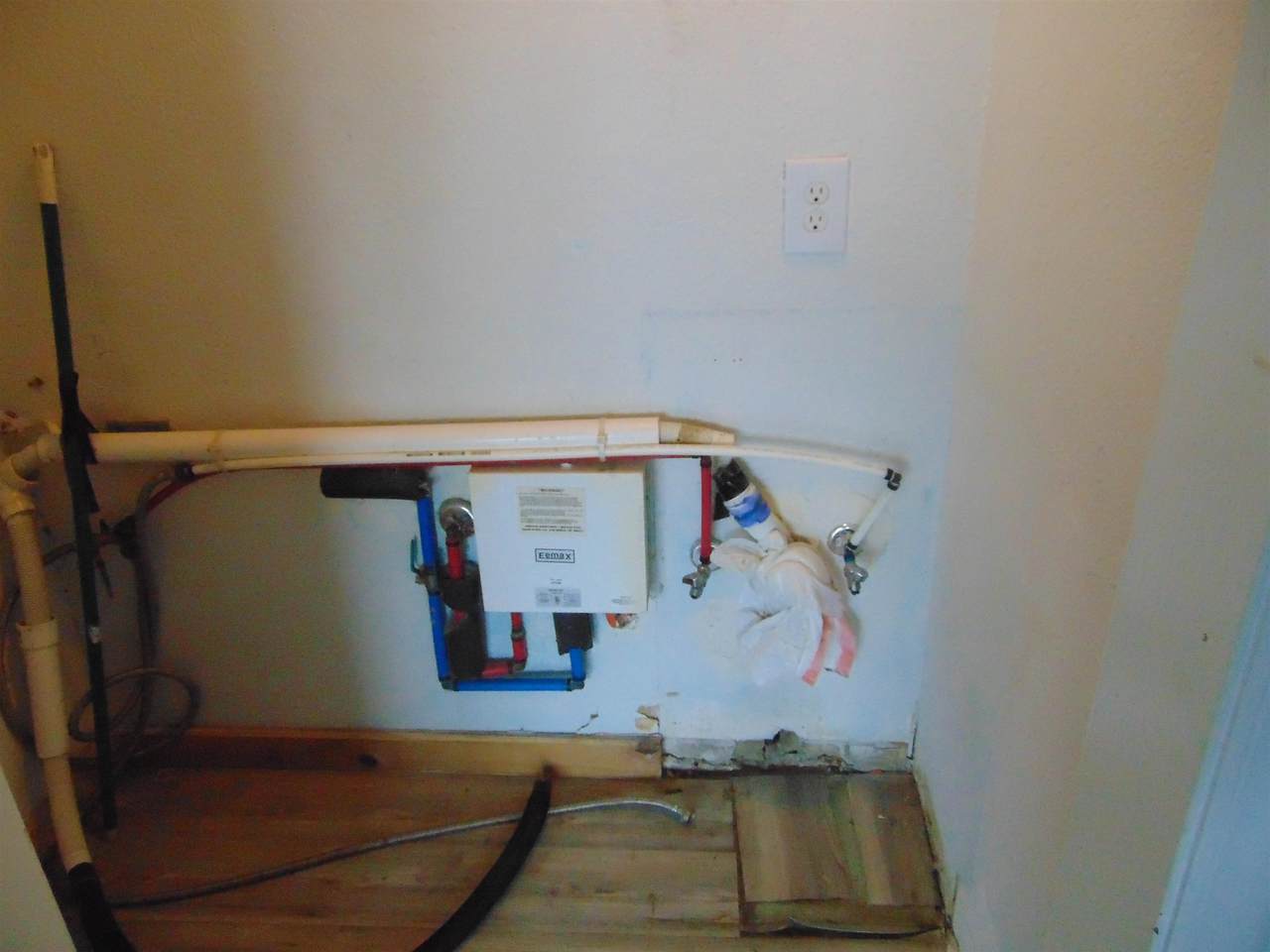 Open utility or vanity area showing exposed plumbing and wall framing
