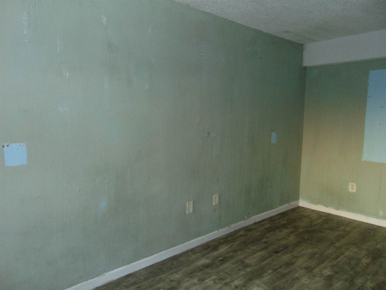 Unfinished living area with vinyl flooring and walls ready for renovation