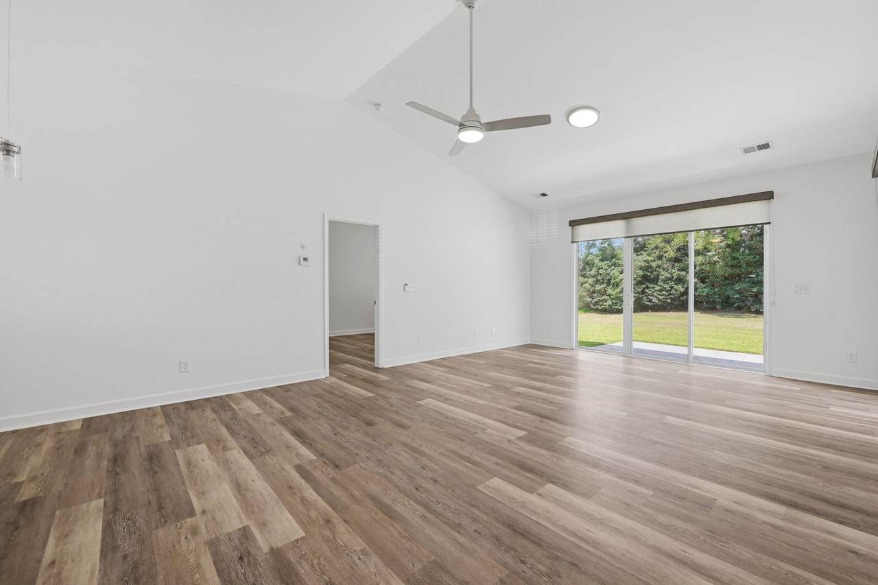 Vaulted living room with light flooring and a ceiling fan