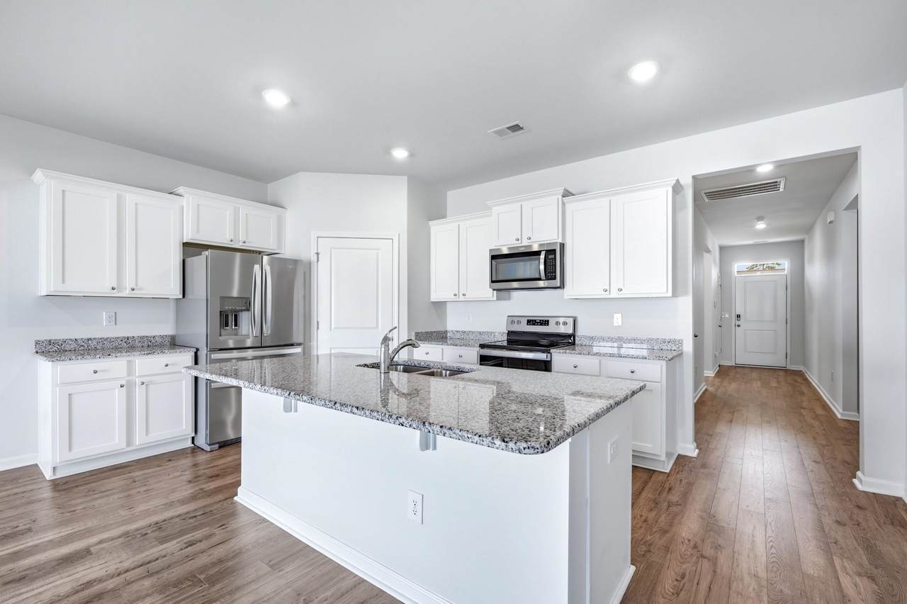 White kitchen with granite island and stainless-steel appliances